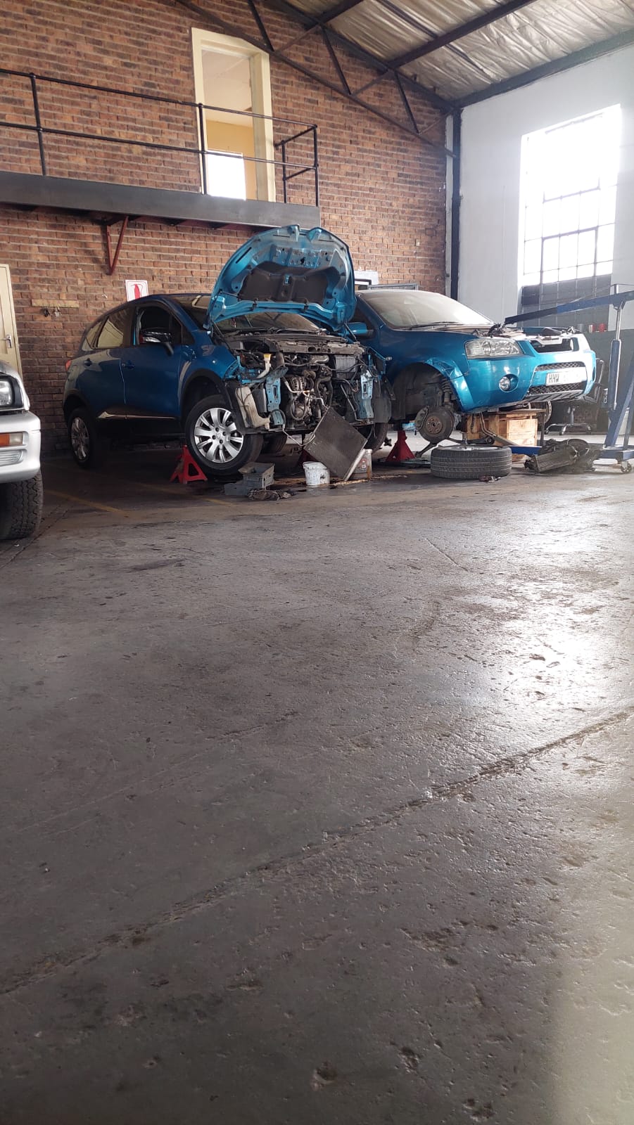 Two vehicles stripped down on stands inside the workshop