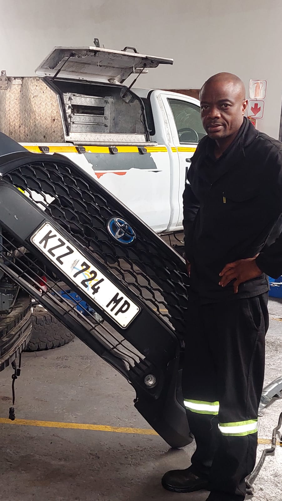 Technician with a Toyota hybrid front bumper removed